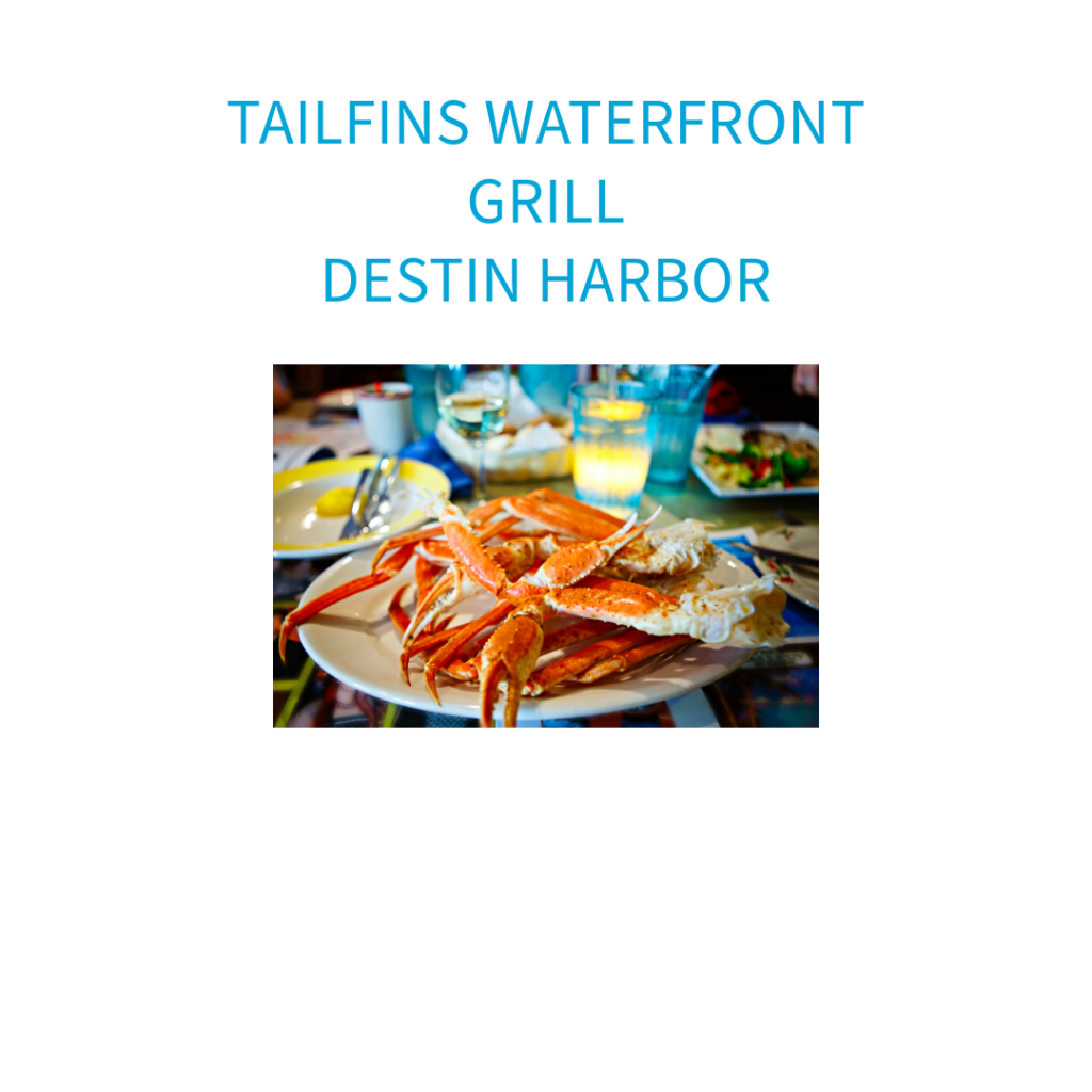 A plate of fresh crab legs served at Tailfins Waterfront Grill in Destin Harbor, with vibrant drinks and a family-friendly atmosphere in the background.